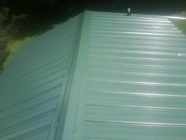 New green metal panels meeting at the ridge of a roof — Flat Roof Repair work by our crew in Cottonton