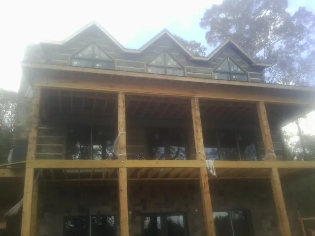 Dormers and porch framing on a large log home under construction — Roof Coating work by our crew in Cottonton