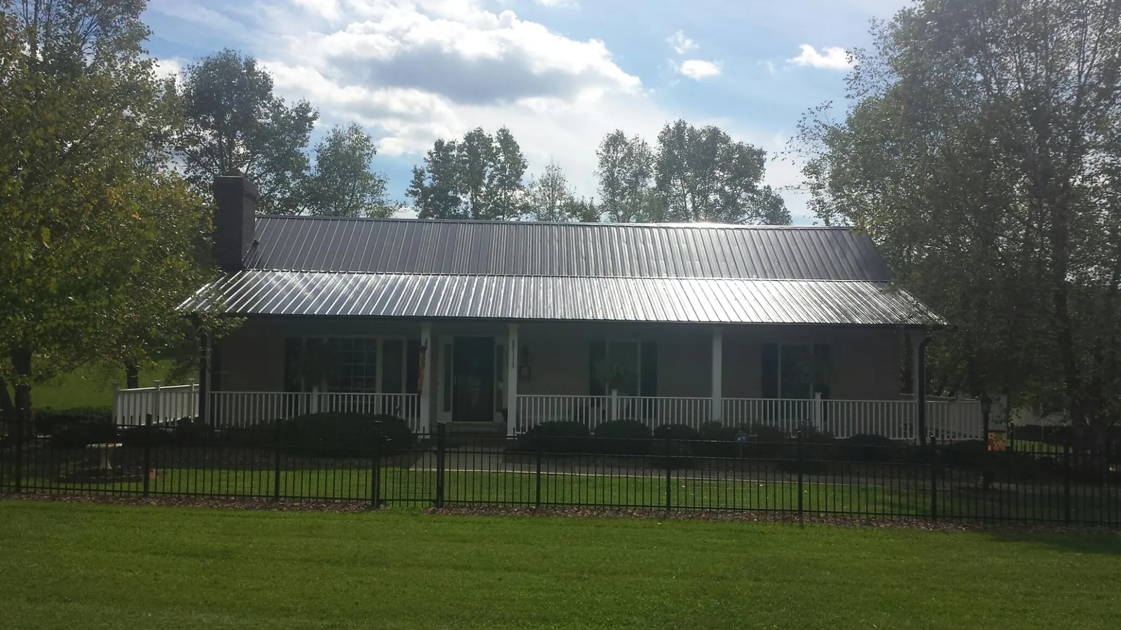 Gray metal roof on a brick ranch with a full width front porch — Gutter Guard Installation work by our crew in Cottonton