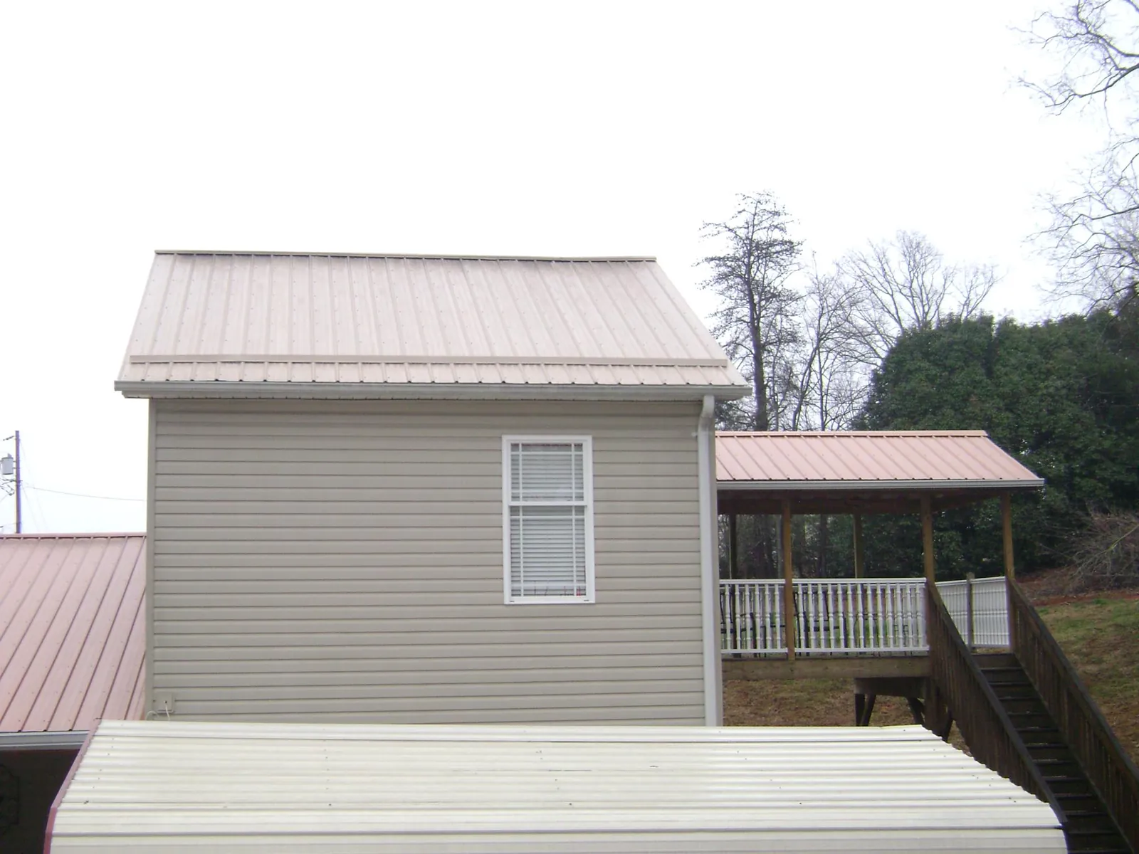 Tan metal roofs on a two story addition and attached porch, from a Roof Replacement job in Cottonton